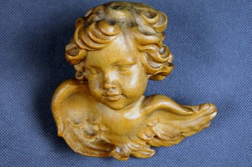 Głowa pięknego amorka wyrzeźbiona w drewnie