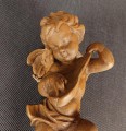 Jasna, drewniana rzeźba przedstawia pulchnego cherubinka grającego na mandolinie. Aniołek jest w ruchu, z uniesioną nogą i przechyloną głową. Widać małe skrzydła i krótkie, kręcone włosy. Całość emanuje radością i muzykalnością.
