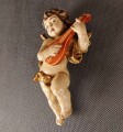 Przedstawiona rzeźba to niewielki, lecz niezwykle ekspresyjny putto – amorkowy posłaniec mitologii – zawieszony w ruchu podczas gry na lutni. Wykonany z drewna rzeźbiarski korpus emanuje autentycznym patynowaniem starej polichromii