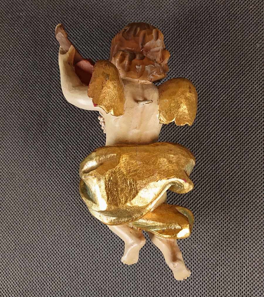 Polichromowana rzeźba z drewna przedstawia amorka ze skrzydełkami, unoszącego się w dynamicznej pozie i grającego na skrzypcach. Jego ciało ma jasną, cielistą barwę. Twarz amorka jest skierowana w stronę widza