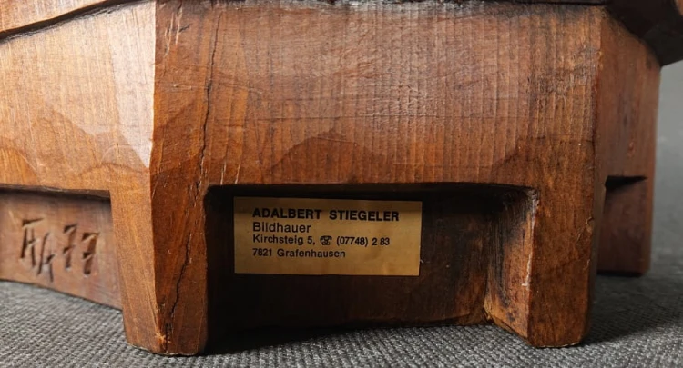 Duża, ręcznie wykonana rzeźba z drewna autorstwa Adalberta Steigelera z 1977 roku przedstawia postać mężczyzny w bogatym, historycznym stroju, inspirowanym XVII-wiecznym kawalerem lub muszkieterem. Rzeźba jest pełnoplastyczna i stoi na prostej podstawie.