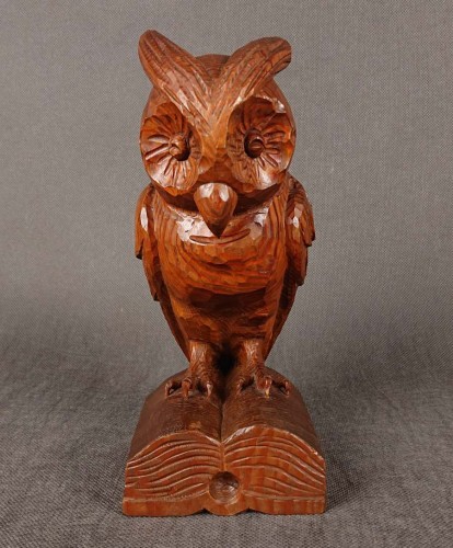 Rzeźba z jednego kawałka, rzeźbionego drewna przedstawia sowę siedzącą na otwartej księdze. Mocne, geometryczne cięcia układają się w fakturę piór skrzydeł i tułowia, podkreślając ich naturalne usłojenie.