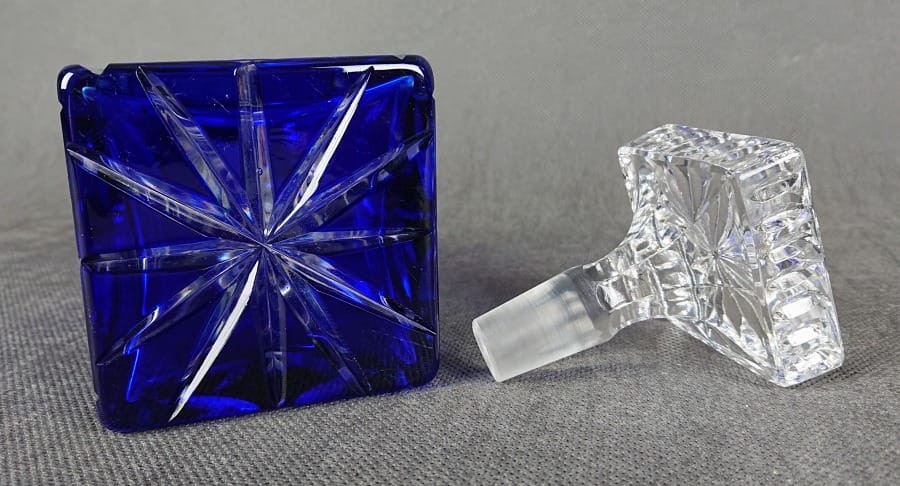 Karafka na alkohol z kryształu z motywami geometrycznymi ze szkła dwuwarstwowego ręcznie formowana i szlifowana, w kolorach bezbarwnym i kobaltowym. Ozdobiona szlifami w formie gwiazdy które kontrastują pomiędzy przezroczystą powierzchnią a kobaltową.