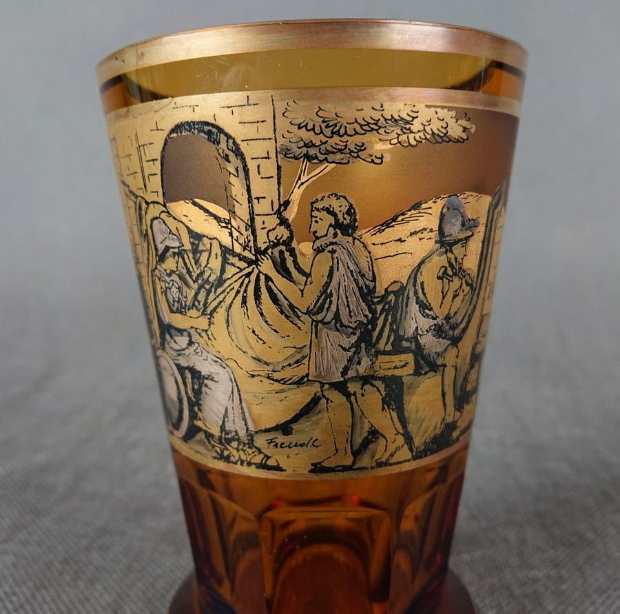 Szklanka, wykonana i ręcznie dekorowana w latach 20-30 XX wieku, prezentuje bogate zdobienie charakterystyczne dla tego okresu. Wykonana jest z miodowego, szkła, które w górnej partii jest matowione, tworząc kontrastującą powierzchnię dla dekoracji.