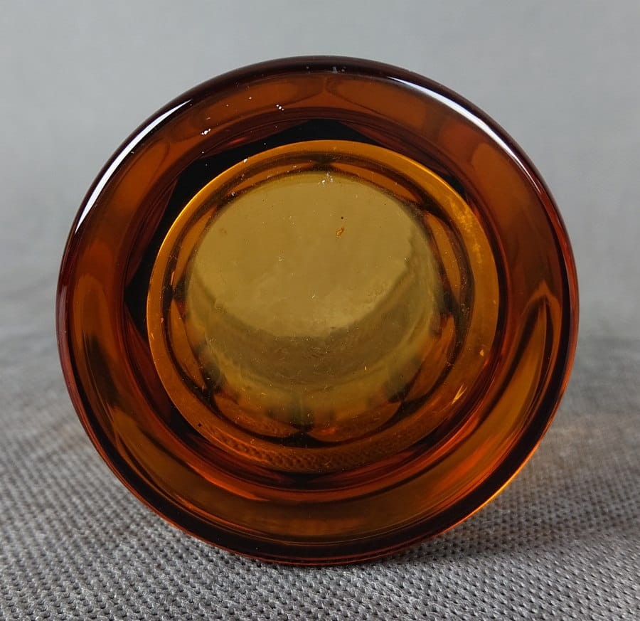 Szklanka, wykonana i ręcznie dekorowana w latach 20-30 XX wieku, prezentuje bogate zdobienie charakterystyczne dla tego okresu. Wykonana jest z miodowego, szkła, które w górnej partii jest matowione, tworząc kontrastującą powierzchnię dla dekoracji.