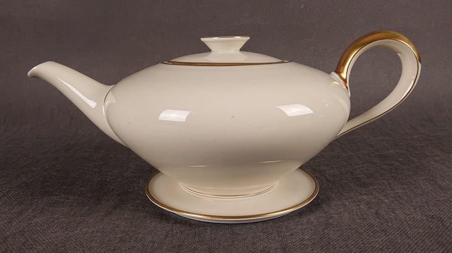 Wykonany z najwyższej jakości porcelany, imbryk do herbaty z podstawką z serwisu. Wykonany w renomowanej niemieckiej wytwórni porcelany, w pięknym odcieniu koloru ecru. Udekorowany imponującymi złoceniami.