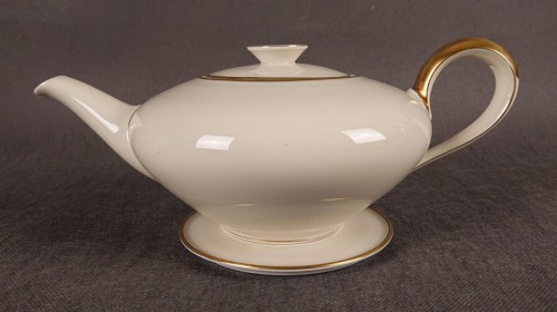 Wykonany z najwyższej jakości porcelany, imbryk do herbaty z podstawką z serwisu. Wykonany w renomowanej niemieckiej wytwórni porcelany, w pięknym odcieniu koloru ecru. Udekorowany imponującymi złoceniami.