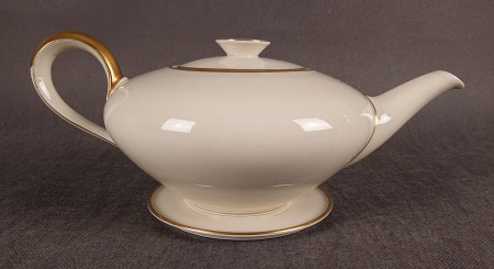 Wykonany z najwyższej jakości porcelany, imbryk do herbaty z podstawką z serwisu. Wykonany w renomowanej niemieckiej wytwórni porcelany, w pięknym odcieniu koloru ecru. Udekorowany imponującymi złoceniami.