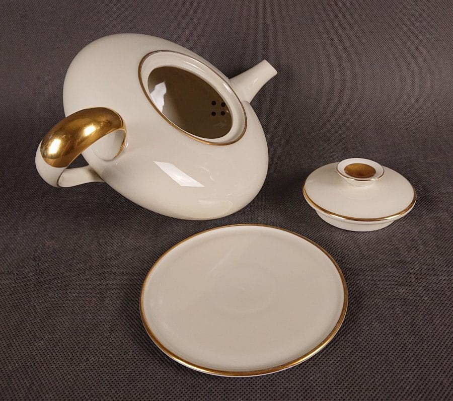 Wykonany z najwyższej jakości porcelany, imbryk do herbaty z podstawką z serwisu. Wykonany w renomowanej niemieckiej wytwórni porcelany, w pięknym odcieniu koloru ecru. Udekorowany imponującymi złoceniami.