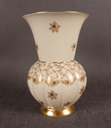 Porcelanowy wazon, wyprodukowany w latach 70-80. XX wieku w bawarskiej Porzellanfabrik Marktredwitz Jäger & Co., charakteryzuje się dwudzielną formą i bogatymi, złoconymi zdobieniami na kremowym tle.