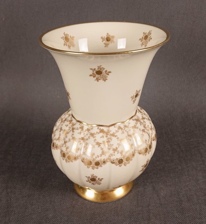 Porcelanowy wazon, wyprodukowany w latach 70-80. XX wieku w bawarskiej Porzellanfabrik Marktredwitz Jäger & Co., charakteryzuje się dwudzielną formą i bogatymi, złoconymi zdobieniami na kremowym tle.