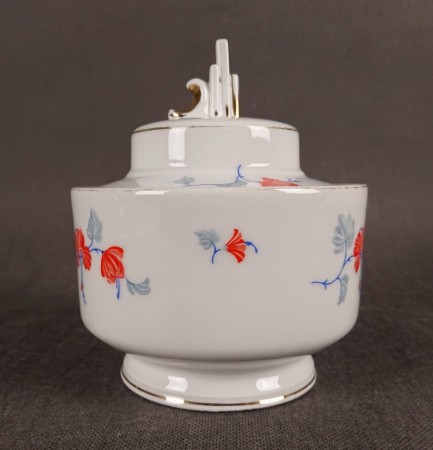 Przedwojenna porcelanowa bomboniera w stylu Art Deco, wyprodukowana w Niemczech przez manufakturę Beyer & Bock w Volkstedt, prezentuje charakterystyczne dla tej epoki połączenie geometrycznych form z delikatnymi zdobieniami.