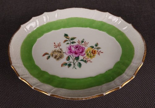 Porcelanowa patera z KPM Berlin, wykonana z białej szkliwionej porcelany, ma owalny kształt z falowanymi brzegami, nawiązującymi do stylu rokoko lub klasycystycznego. Krawędź patery jest podkreślona złoceniem, co dodaje jej elegancji.