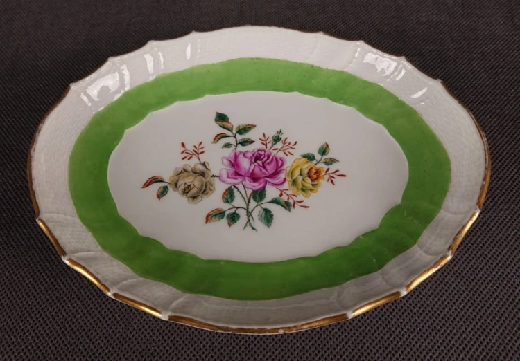 Porcelanowa patera z KPM Berlin, wykonana z białej szkliwionej porcelany, ma owalny kształt z falowanymi brzegami, nawiązującymi do stylu rokoko lub klasycystycznego. Krawędź patery jest podkreślona złoceniem, co dodaje jej elegancji.