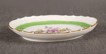 Porcelanowa patera z KPM Berlin, wykonana z białej szkliwionej porcelany, ma owalny kształt z falowanymi brzegami, nawiązującymi do stylu rokoko lub klasycystycznego. Krawędź patery jest podkreślona złoceniem, co dodaje jej elegancji.