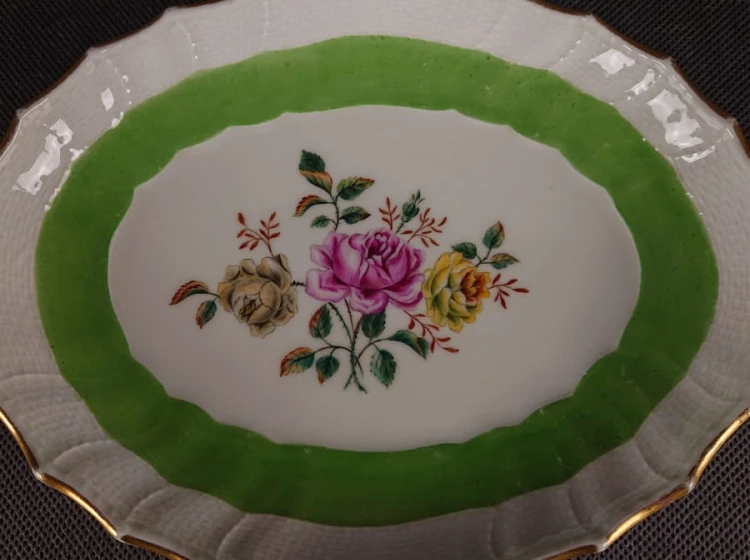 Porcelanowa patera z KPM Berlin, wykonana z białej szkliwionej porcelany, ma owalny kształt z falowanymi brzegami, nawiązującymi do stylu rokoko lub klasycystycznego. Krawędź patery jest podkreślona złoceniem, co dodaje jej elegancji.