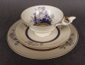 Przedwojenny zestaw śniadaniowy z niemieckiej fabryki porcelany Hertel Jacob. składa się z filiżanki, spodka i talerza deserowego. Zestaw charakteryzuje się elegancką, kremową porcelaną oraz delikatnymi zdobieniami w odcieniach błękitu, szarości i złota.