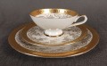Porcelanowy zestaw śniadaniowy z niemieckiej fabryki Hertel Jacob & Co. to elegancki komplet składający się z filiżanki, spodka i talerza deserowego. Wykonana z białej, szkliwionej porcelany i bogato zdobiona złotymi, reliefowymi i malowanymi wzorami.