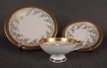 Porcelanowy zestaw śniadaniowy z niemieckiej fabryki Hertel Jacob & Co. to elegancki komplet składający się z filiżanki, spodka i talerza deserowego. Wykonana z białej, szkliwionej porcelany i bogato zdobiona złotymi, reliefowymi i malowanymi wzorami.