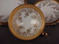 Porcelanowy zestaw śniadaniowy z niemieckiej fabryki Hertel Jacob & Co. to elegancki komplet składający się z filiżanki, spodka i talerza deserowego. Wykonana z białej, szkliwionej porcelany i bogato zdobiona złotymi, reliefowymi i malowanymi wzorami.