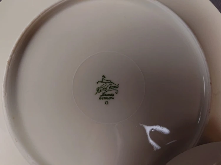 Zestaw śniadaniowy z niemieckiej fabryki porcelany Hertel Jacob & Co. to elegancki komplet składający się z filiżanki, spodka i talerza deserowego. Elementy wykonane są z białej, szkliwionej porcelany i zdobione motywami ostów i złotymi akcentami.