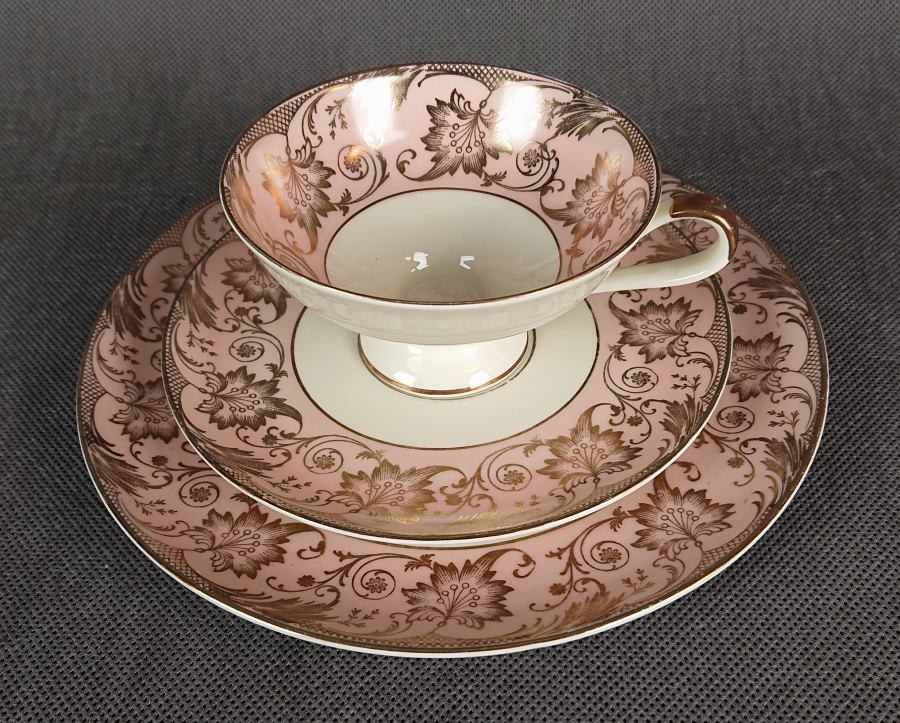Uroczy zestaw śniadaniowy, o pięknych klasycznych kształtach. Wykonany z bardzo wysokiej klasy porcelany w kolorze ecru. Zestaw składa się z talerzyka deserowego, spodka i filiżanki. Udekorowana na pudrowo różowym tle bogatymi złoconymi.