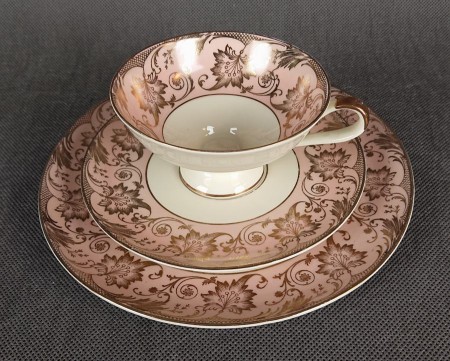 Uroczy zestaw śniadaniowy, o pięknych klasycznych kształtach. Wykonany z bardzo wysokiej klasy porcelany w kolorze ecru. Zestaw składa się z talerzyka deserowego, spodka i filiżanki. Udekorowana na pudrowo różowym tle bogatymi złoconymi.