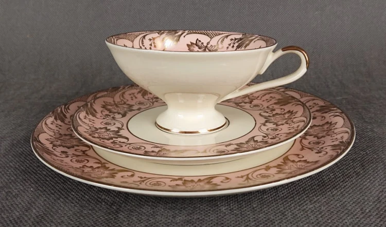 Uroczy zestaw śniadaniowy, o pięknych klasycznych kształtach. Wykonany z bardzo wysokiej klasy porcelany w kolorze ecru. Zestaw składa się z talerzyka deserowego, spodka i filiżanki. Udekorowana na pudrowo różowym tle bogatymi złoconymi.