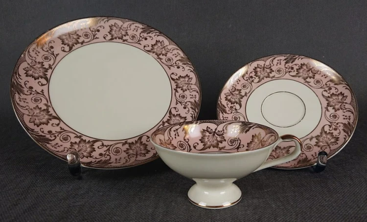 Uroczy zestaw śniadaniowy, o pięknych klasycznych kształtach. Wykonany z bardzo wysokiej klasy porcelany w kolorze ecru. Zestaw składa się z talerzyka deserowego, spodka i filiżanki. Udekorowana na pudrowo różowym tle bogatymi złoconymi.