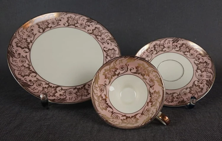 Uroczy zestaw śniadaniowy, o pięknych klasycznych kształtach. Wykonany z bardzo wysokiej klasy porcelany w kolorze ecru. Zestaw składa się z talerzyka deserowego, spodka i filiżanki. Udekorowana na pudrowo różowym tle bogatymi złoconymi.