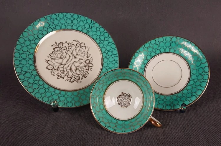Śliczny zestaw śniadaniowy, o pięknych klasycznych kształtach. Wykonany z bardzo wysokiej klasy porcelany w kolorze ecru. Zestaw składa się z talerzyka deserowego, spodka i filiżanki. Udekorowana na zielonym tle bogatymi złoconymi.