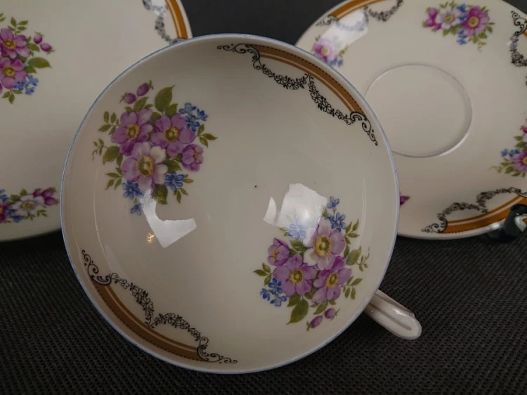 Zestaw niemieckiej firmy Johann Seltmann z lat 40. XX w. składa się z filiżanki, małego spodka i talerzyka deserowego. Wykonany z kremowej porcelany. Wnętrze filiżanki i ranty talerzy zdobią delikatne girlandy kwiatów w odcieniach lila, różu i błękitu.