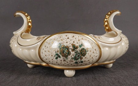 Duża porcelanowa patera w formie żardiniery, wyprodukowana w Neue Porzellanfabrik Tettau AG w latach 1935-1948, z bogatymi zdobieniami i klasyczną formą  Patera ma wydłużony, owalny kształt, rozszerzający się ku górze.