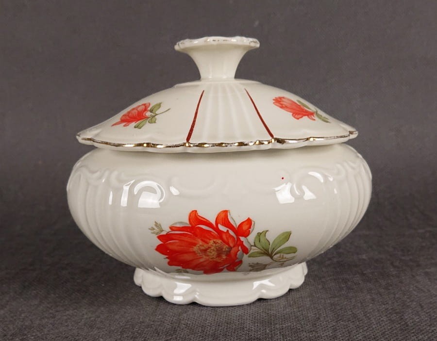 Duża bomboniera w stylu art-deco z porcelany, pochodząca z Dolnego Śląska. Wykonana z porcelany w kolorze ecru o kulistej formie wsparta podstawie w formie falbany, na szczególną uwagę zasługuje finezyjny uchwyt na pokrywce.