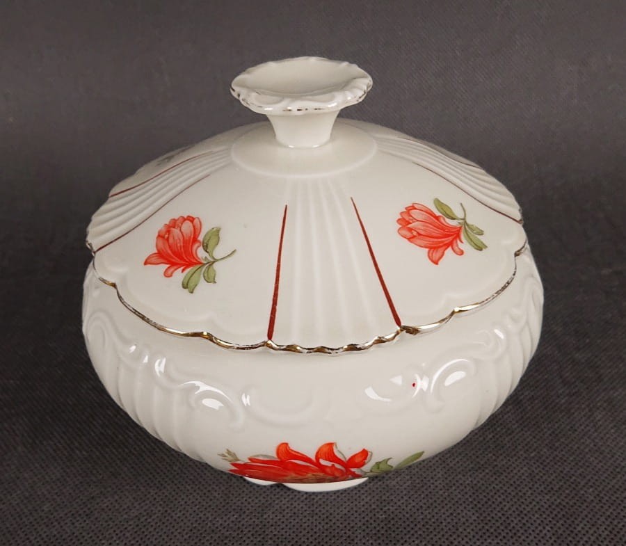 Duża bomboniera w stylu art-deco z porcelany, pochodząca z Dolnego Śląska. Wykonana z porcelany w kolorze ecru o kulistej formie wsparta podstawie w formie falbany, na szczególną uwagę zasługuje finezyjny uchwyt na pokrywce.