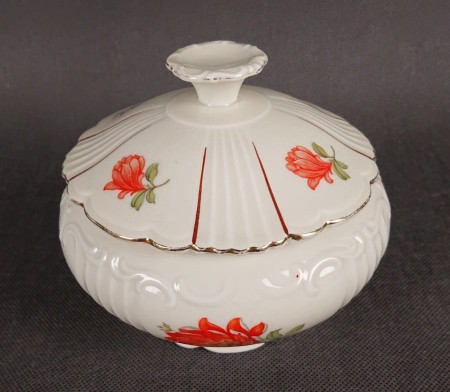 Duża bomboniera w stylu art-deco z porcelany, pochodząca z Dolnego Śląska. Wykonana z porcelany w kolorze ecru o kulistej formie wsparta podstawie w formie falbany, na szczególną uwagę zasługuje finezyjny uchwyt na pokrywce.
