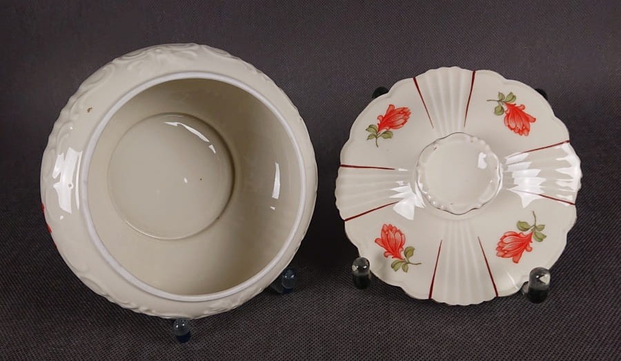 Duża bomboniera w stylu art-deco z porcelany, pochodząca z Dolnego Śląska. Wykonana z porcelany w kolorze ecru o kulistej formie wsparta podstawie w formie falbany, na szczególną uwagę zasługuje finezyjny uchwyt na pokrywce.