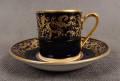 Filiżanka ze spodkiem do kawy espresso, pochodzi z drugiej połowy XX. wieku. Zestaw wykonany z wyjątkowo delikatnej dobrej jakości cienkiej białej porcelany.  Filiżanka i spodek dekorowana kobaltem a na tym tle złote dekoracja.