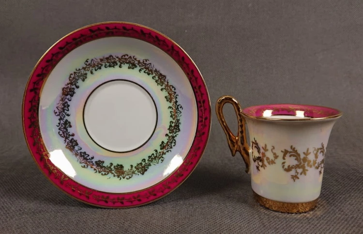 Espresso filiżanka ze scenką Martinroda Fridrich. Porcelanowa filiżanka ze spodkiem do espresso, wyprodukowana w niemieckiej fabryce porcelany Martinroda, prezentuje wyrafinowany styl rokoko, charakteryzuje się bogatym zdobieniami i perłowym połyskiem.