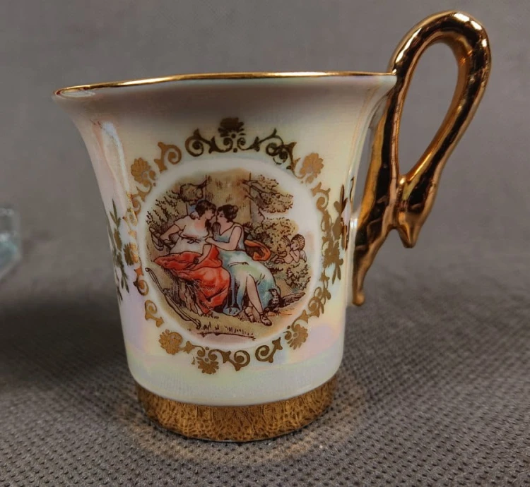Espresso filiżanka ze scenką Martinroda Fridrich. Porcelanowa filiżanka ze spodkiem do espresso, wyprodukowana w niemieckiej fabryce porcelany Martinroda, prezentuje wyrafinowany styl rokoko, charakteryzuje się bogatym zdobieniami i perłowym połyskiem.