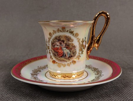 Espresso filiżanka ze scenką Martinroda Fridrich. Porcelanowa filiżanka ze spodkiem do espresso, wyprodukowana w niemieckiej fabryce porcelany Martinroda, prezentuje wyrafinowany styl rokoko, charakteryzuje się bogatym zdobieniami i perłowym połyskiem.