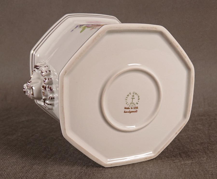 Na spodzie osłonki znajduje się zielona pieczęć z napisem „Lichte Fine China”, symbolem z gwiazdą oraz informacjami „Made in GDR” (Wyprodukowano w NRD) i „handgemalt” (ręcznie malowane).