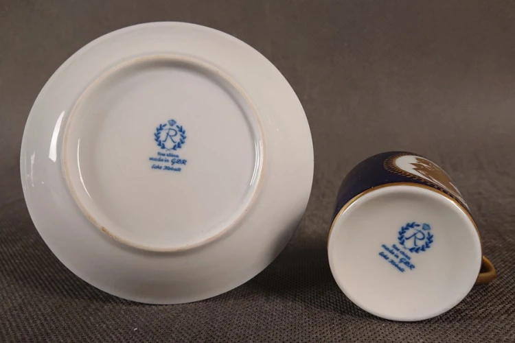 Symbol: Litera „R” wpisana w wieniec laurowy, zwieńczona koroną – znak towarowy manufaktury Reichenbach. Napisy: „fine china”, „made in G.D.R.” (wyprodukowano w NRD) oraz „Echt Kobalt”.