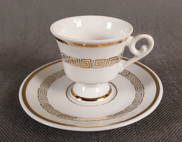 Ten elegancki zestaw do espresso to klasyczny przykład niemieckiej porcelany dekoracyjnej, łączący surową biel z bogatym, złotym zdobnictwem.