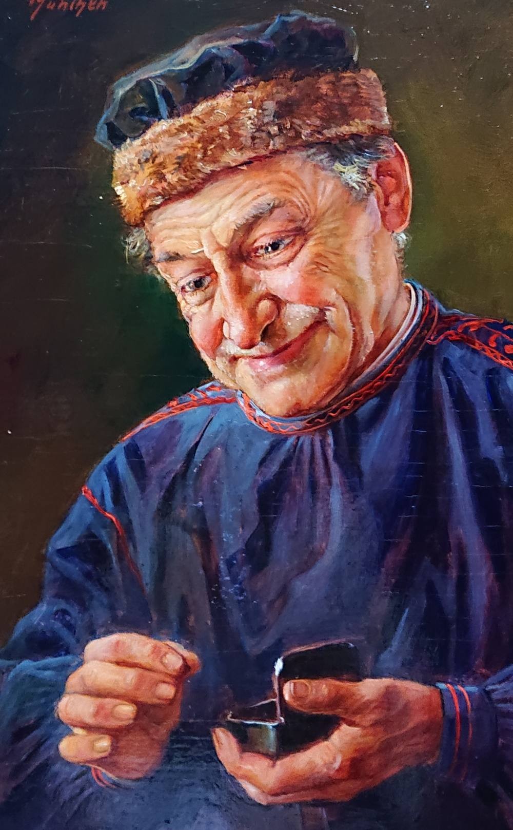 Postać ubrana jest w ciemny, ludowy kaftan z czerwonymi akcentami haftu oraz futrzaną czapką, co nadaje scenie regionalnego, środkowoeuropejskiego kolorytu i podkreśla typowość modela – „człowieka z ludu”.