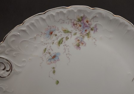 Zbliżenie na pastelowy bukiet niebieskich i fioletowych kwiatów na tle śnieżnobiałej porcelany