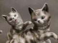 Bliskie ujęcie na głowy porcelanowych kotów z widocznymi szmaragdowymi oczami z lat 10. XX wieku