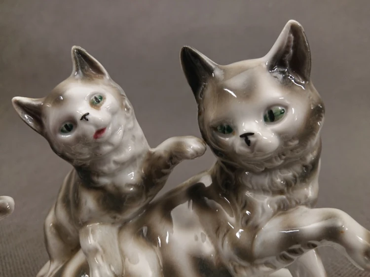 Bliskie ujęcie na głowy porcelanowych kotów z widocznymi szmaragdowymi oczami z lat 10. XX wieku