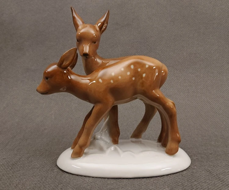 Porcelanowa figurka przedstawiająca parkę brązowych sarenek na białym cokoliku, widok z boku