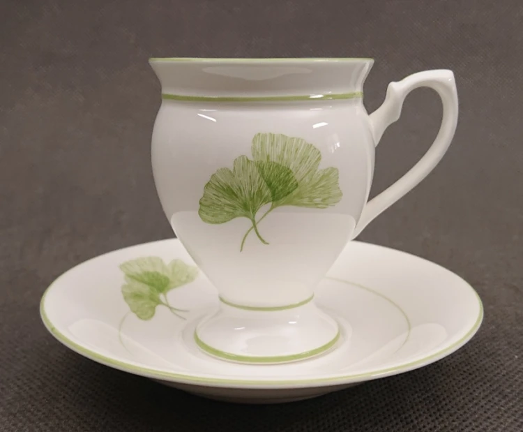 Porcelanowa biała filiżanka ze spodkiem Royal Astor Ginko z zielonym motywem miłorzębu